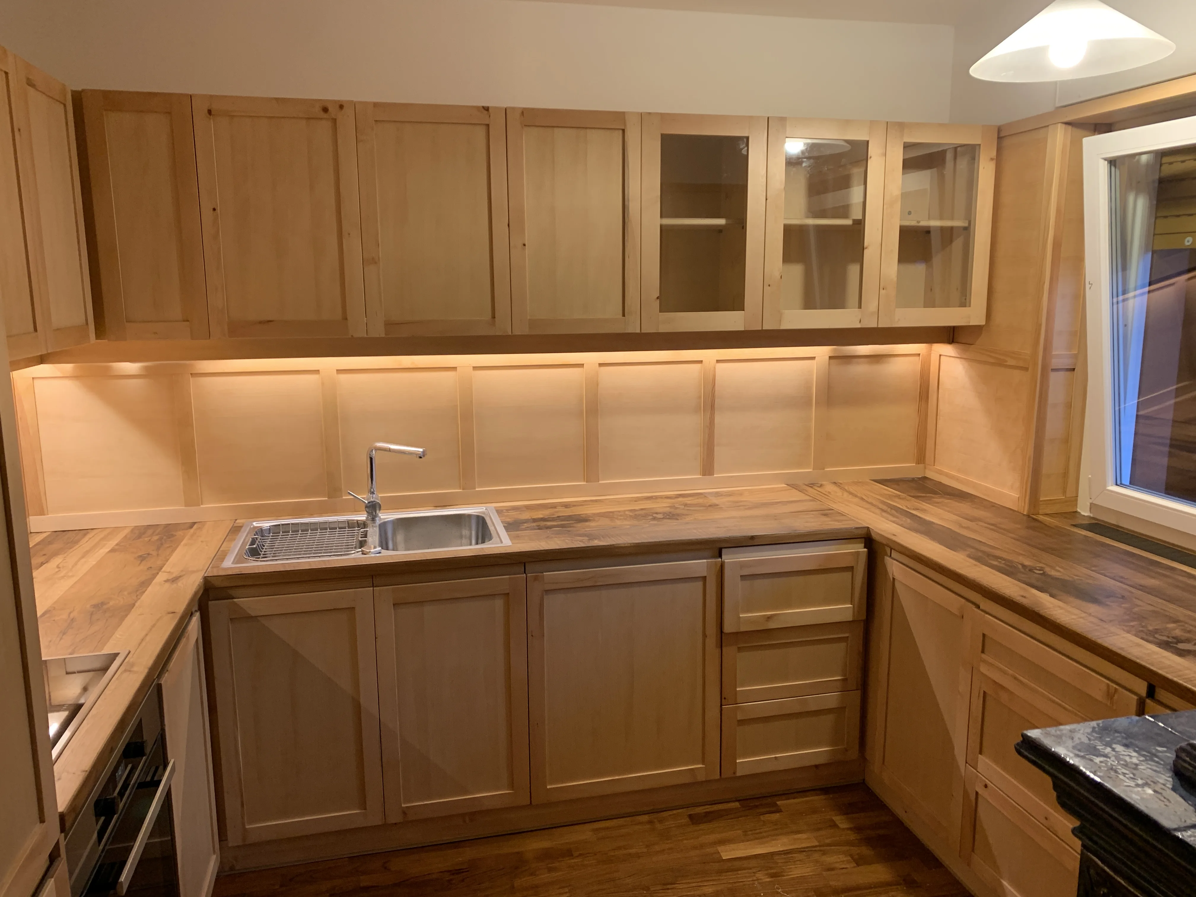 Cucina in legno chiaro con ante a vetro, piano di lavoro in legno antico e isola centrale