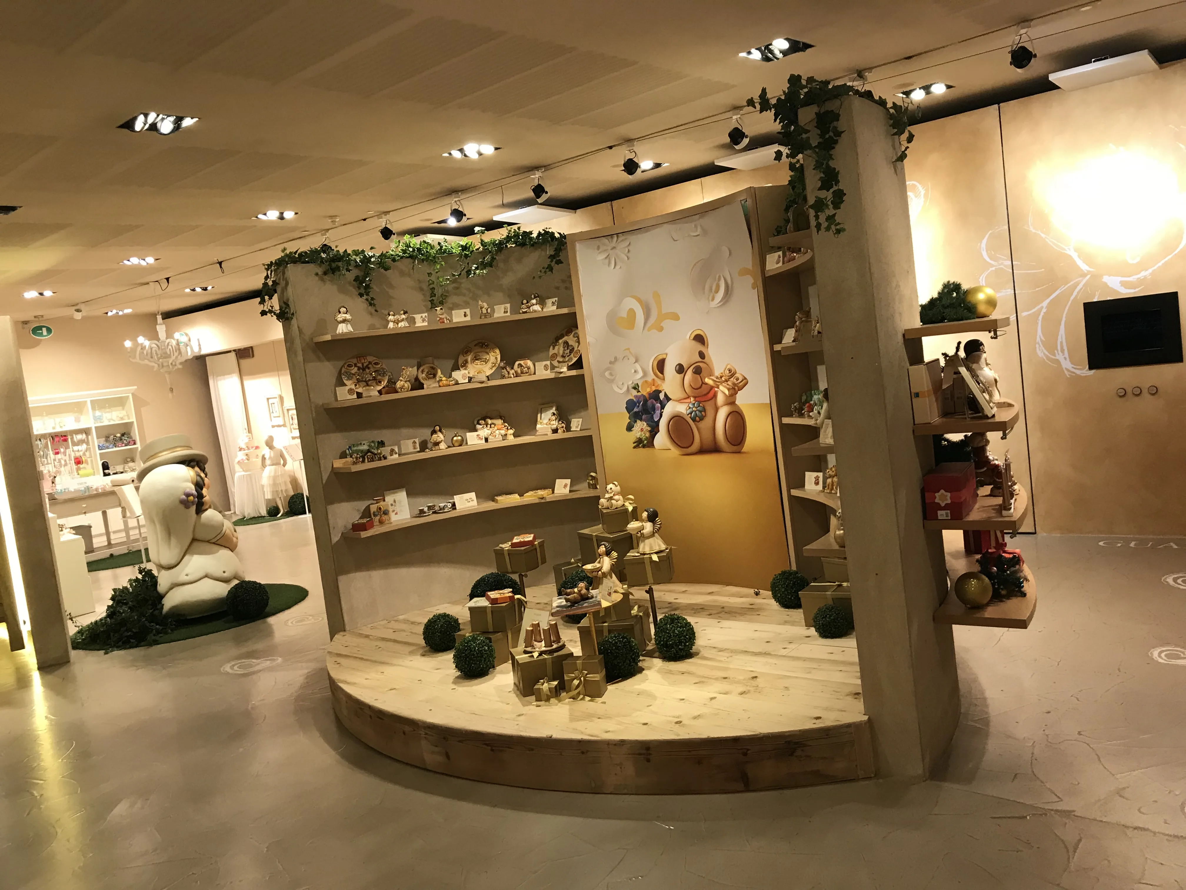 Pavimento e arredi in legno chiaro in un ambiente espositivo con mensole a parete